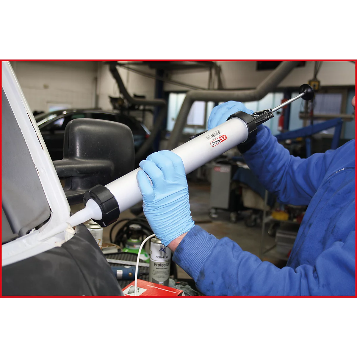 Person trägt mit Handschuhen eine Kartuschenpistole zur Abdichtung an einem Fahrzeug an.